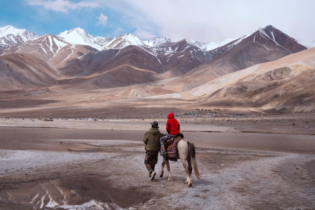 A person and child riding a horse in the breathtaking mountains of Ladakh, India.